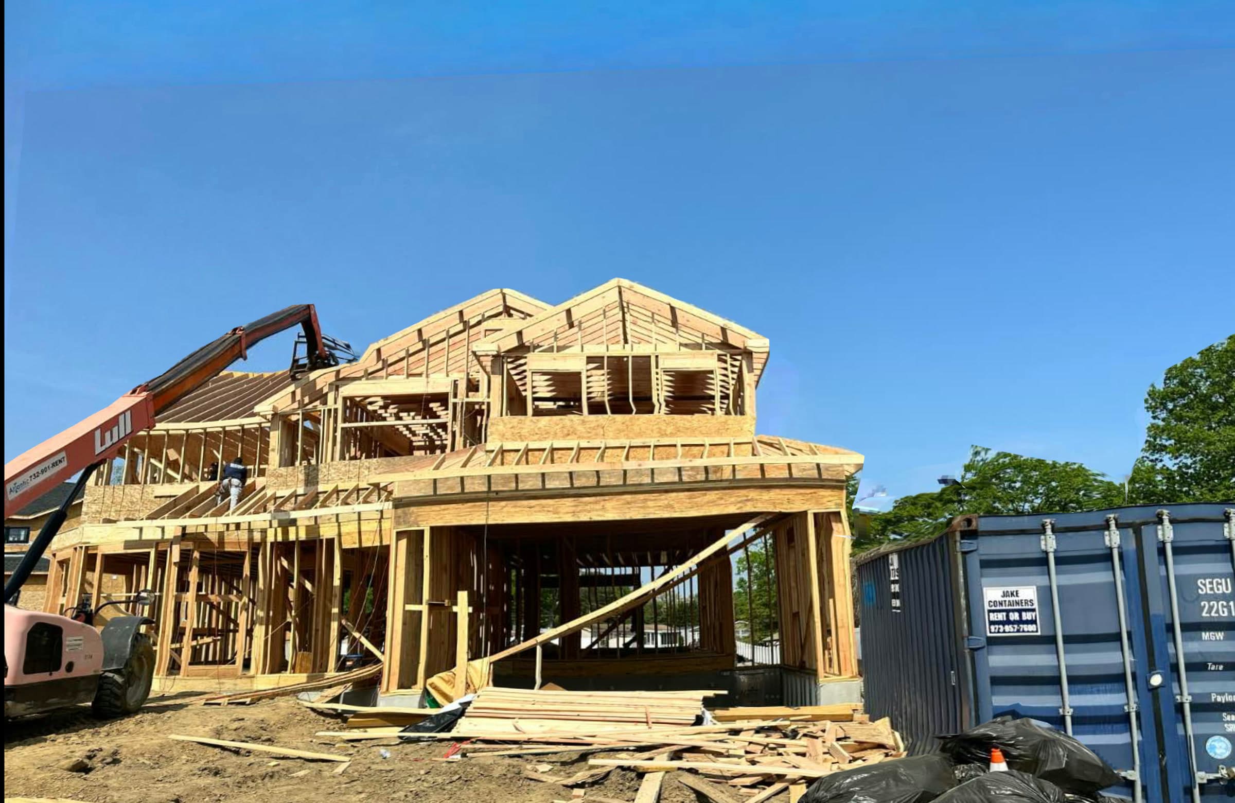 Two-story home in wood framing with a telehandler setting roof panels on a BayfordBridge parcel