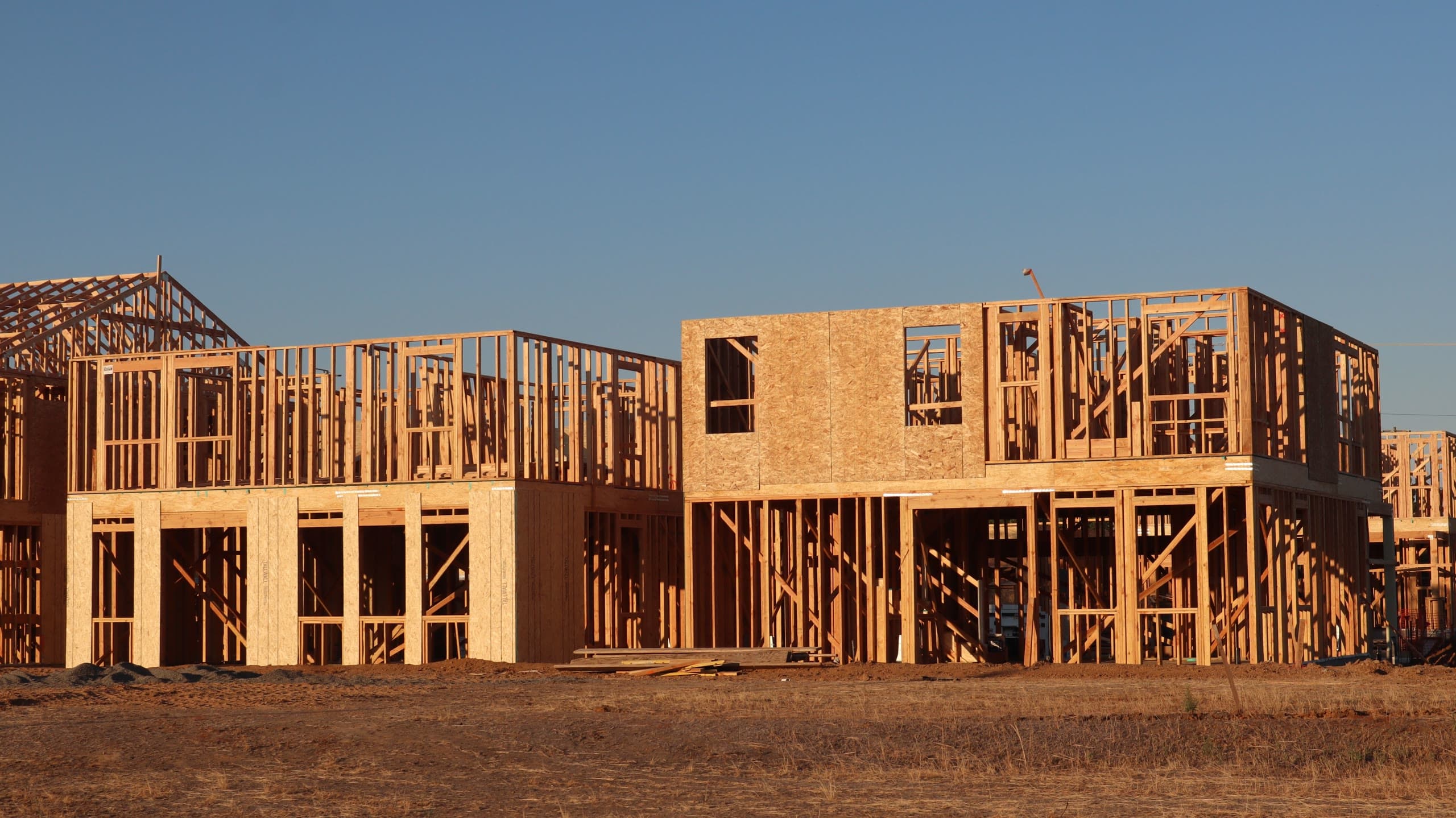 Two-story homes in wood framing at golden hour on a graded site